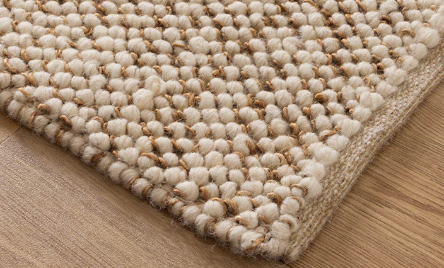 Close-up of a woven rug corner on a wooden floor