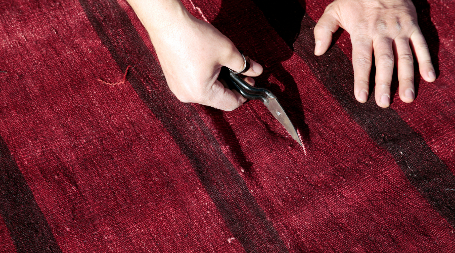 Hands trimming thread on a red geometric-pattern textile
