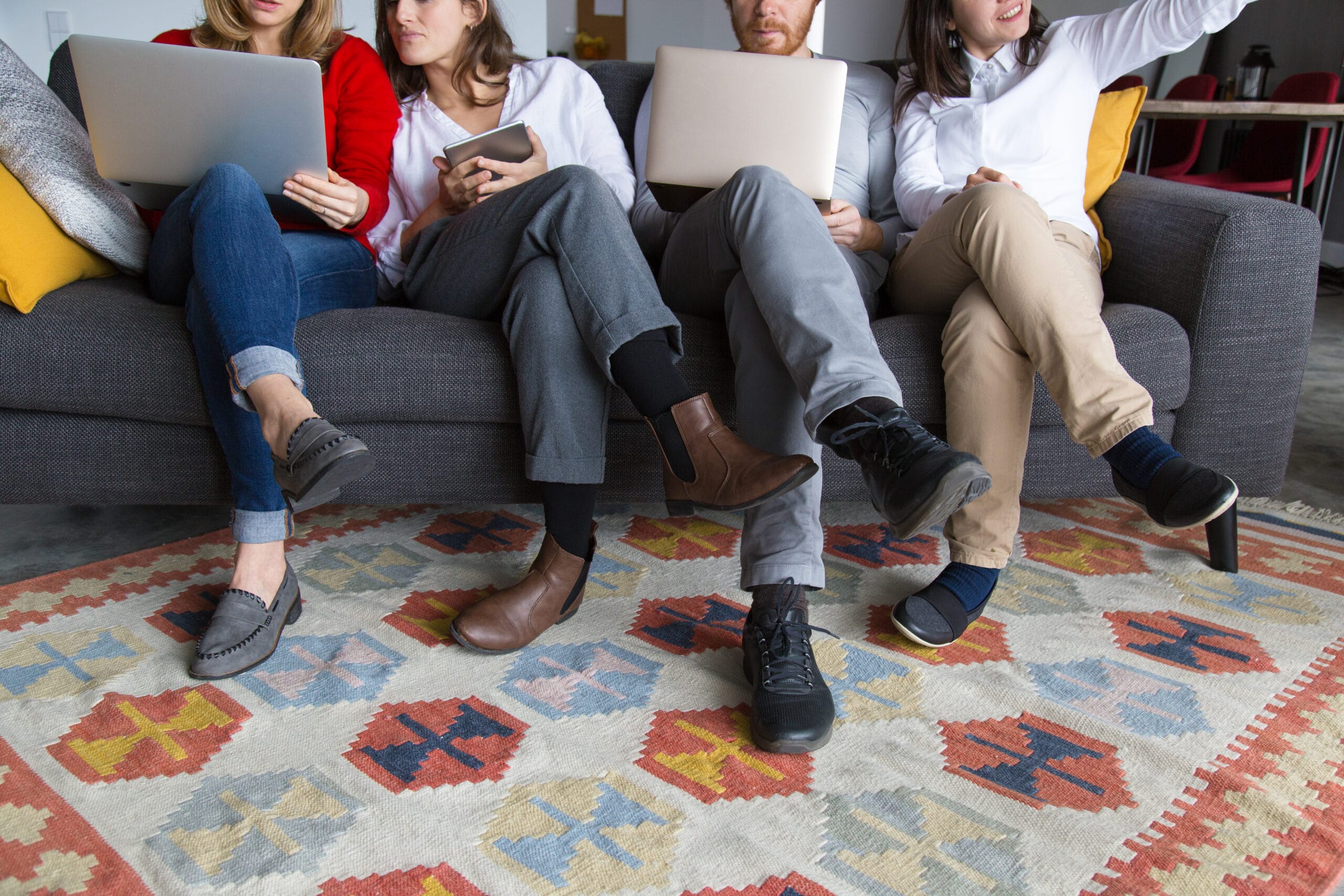 Four people with laptops resting their feet on a kilim rug