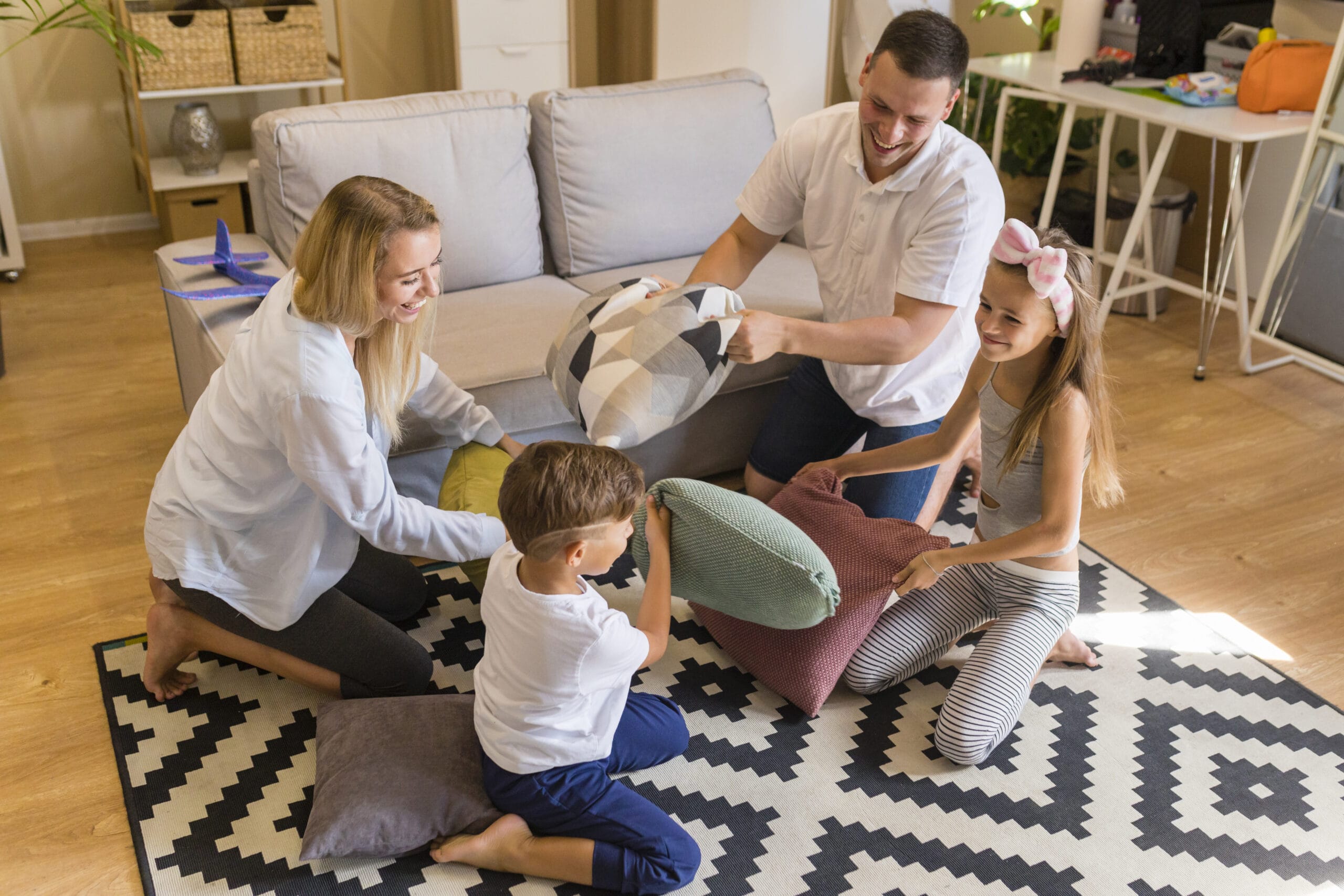 Family having a pillow fight on a black and cream patterned rug