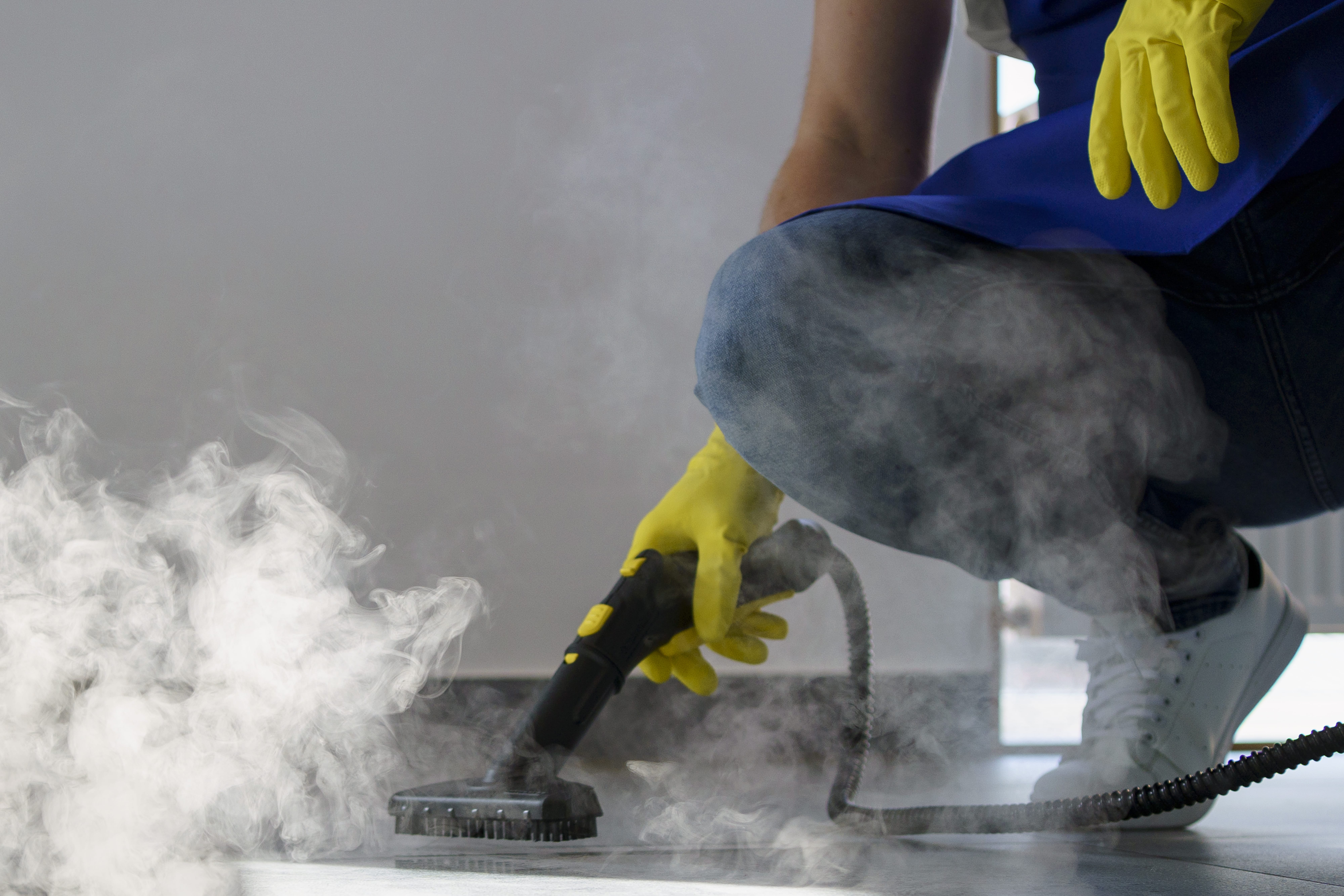 Worker using a steam cleaner on a floor