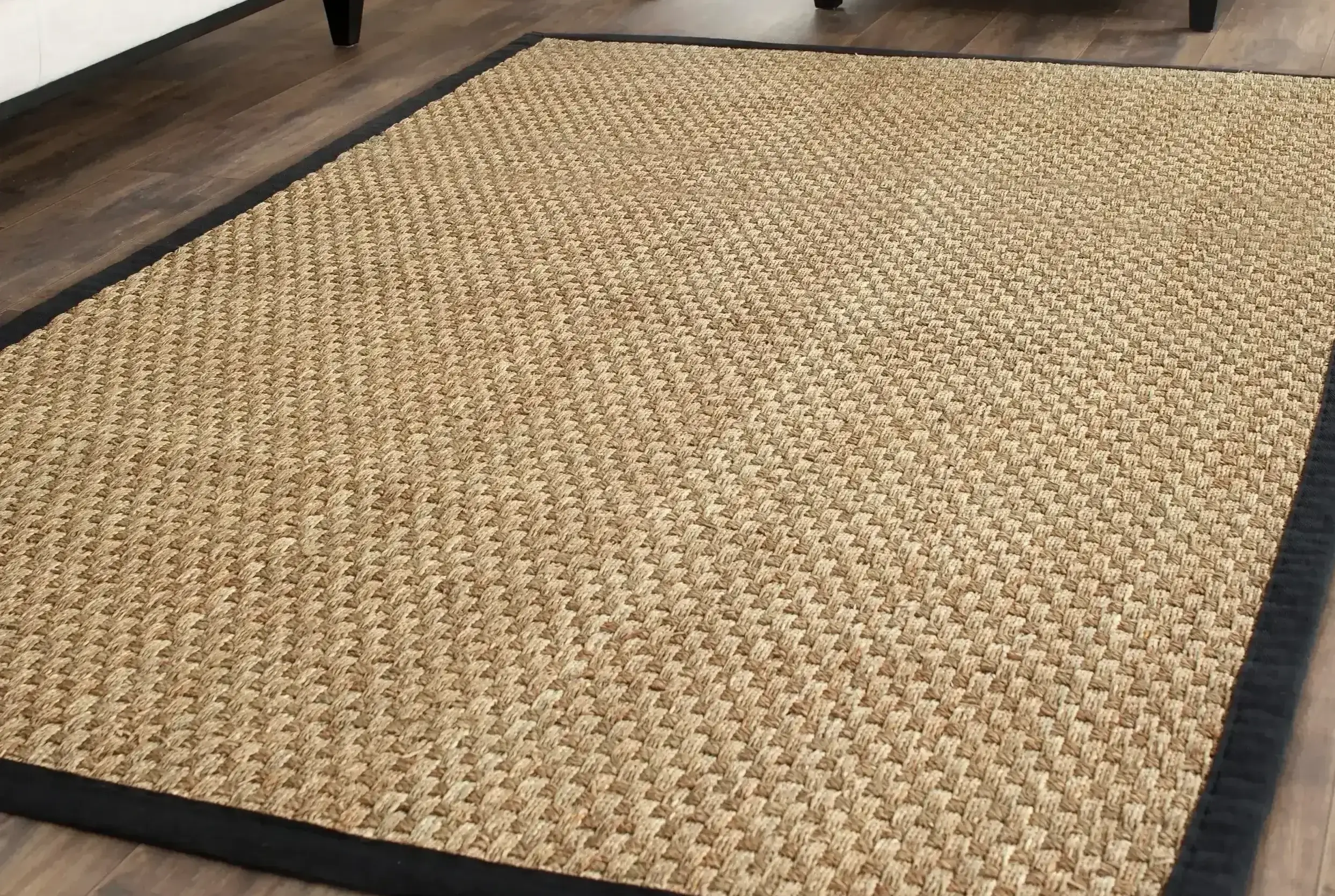 Tan basket-weave seagrass rug with a black border