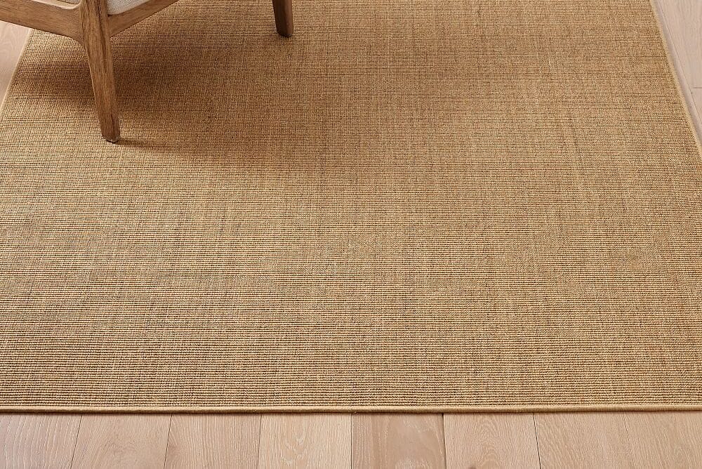 Tan sisal rug beside a wooden chair leg