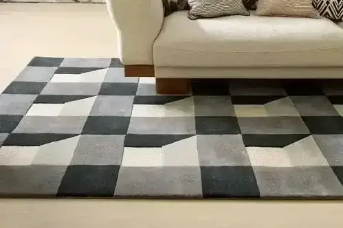 Grey and cream geometric tufted rug beside a sofa