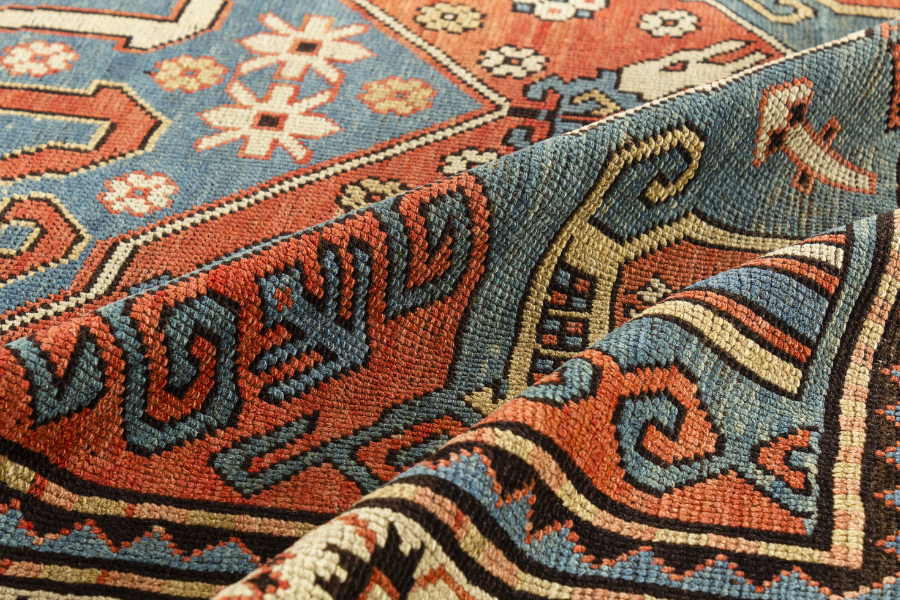 Folded corner of an antique red and blue patterned rug