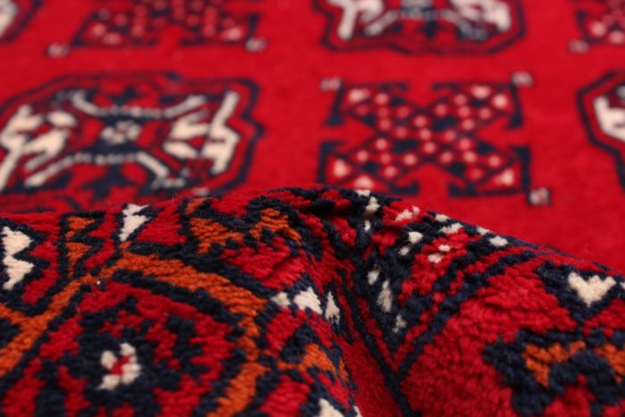 Close-up of a red rug with navy geometric cross motifs