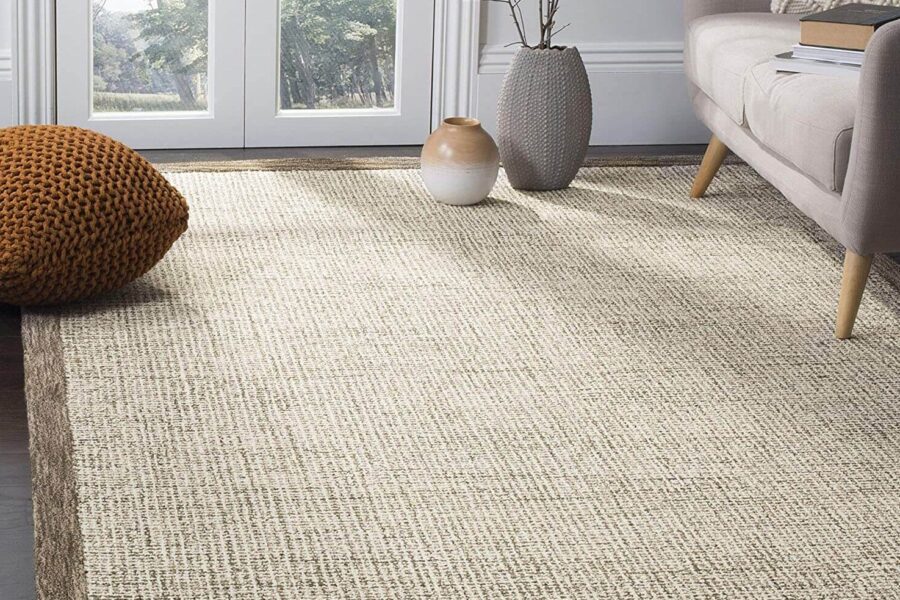 Cream wool area rug with a brown border in a living room